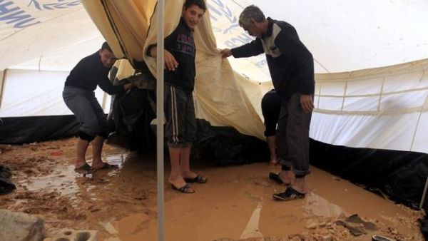 Syrian refugees try to remove water which had collected inside their tent after heavy rain in the Zaatari refugee camp. (AFP PHOTO/KHALIL MAZRAAWI)