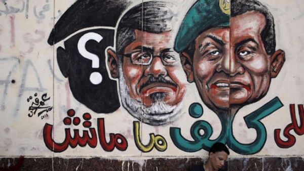 An opposition demonstrator sits below graffiti of Egyptian President Morsi on the walls of Egypt's Presidential Palace in Cairo, Egypt. (Image: by Ed Giles/Getty Images)