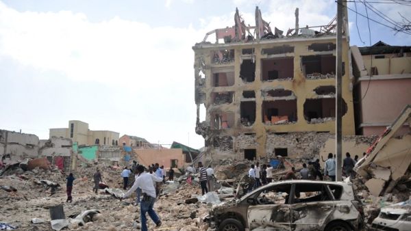 People react and walk among rubbles following an attack outside an hotel on January 25, 2017, in Mogadishu. At least seven people were killed after two car bombs exploded outside a popular Mogadishu hotel and gunmen forced their way inside the building and opened fire, police said. (AFP/Mohamed Abdiwahab)