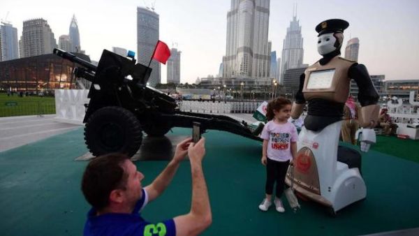 Ahead of the game. A 2017 file picture shows people taking a picture with the world’s first operational police robot near the Burj Khalifa in Dubai. (AFP)