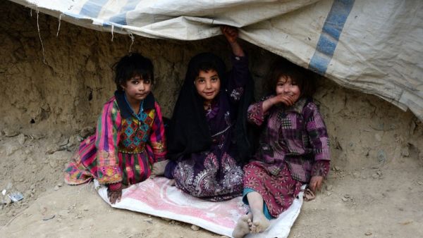 Internally displaced Afghan children sit outside their temporary home at a refugee camp in Kabul on December 16, 2016. (AFP/Noorullah Shirzada)