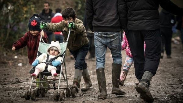 A young boy pushes his sibling through the mud at a makeshift camp close to Calais.0 (AFP/File)