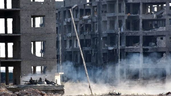 Syrian pro-government forces drive past heavily damaged buildings in Aleppo on November 8, 2016. (AFP/Georges Ourfalian)