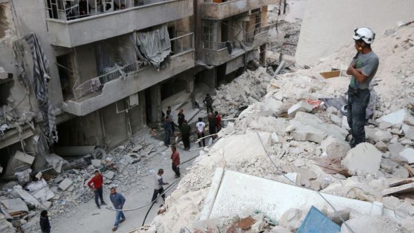 A Syrian civil defence volunteer, known as the White Helmets, stands on the rubble of destroyed buildings during a rescue operation following a government forces air strike on the rebel-held neighbourhood of Bustan al-Basha in Aleppo. (AFP/Thaer Mohammed)