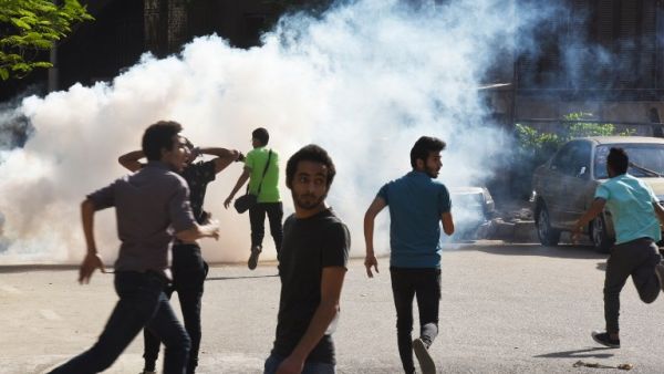 Egyptian protesters run for cover from tear gas fired by riot police during a Cairo demonstration, April 25, 2016. (AFP/Mohamed el-Shahed)
