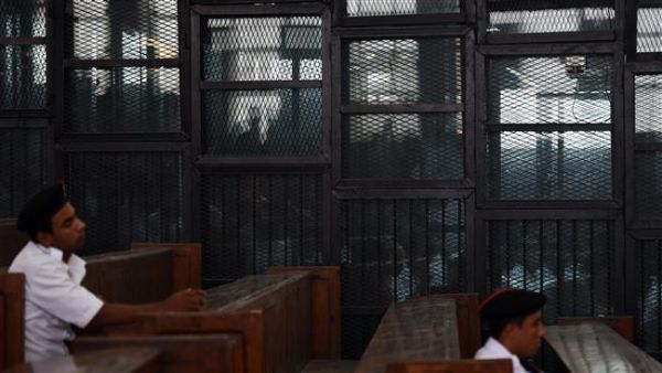 Egyptian Muslim Brotherhood defendants, including leader Mohamed Badie, stand behind bars during a trial in Cairo on August 22, 2015. (AFP/File) 