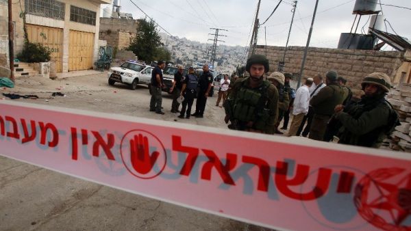 Israeli security forces gather at the scene where a Palestinian stabbed an Israeli soldier before he was shot dead, in the flashpoint West Bank city of Hebron. (AFP/Hazem Bader)