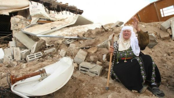 A Palestinian woman sits next to the remains of her home after it was demolished by Israeli bulldozers in the West Bank town of Hebron. (AFP/File) 