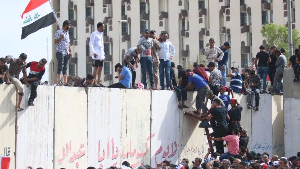 Iraqi protesters climb over a concrete wall surrounding the parliament after breaking into Baghdad's heavily fortified "Green Zone" on April 30, 2016. (AFP/Haidar Mohammed Ali)