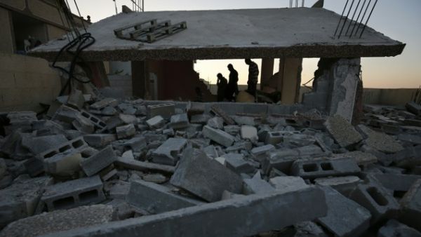 Palestinians stand near a house that was demolished by Israeli authorities in the Qalandia refugee camp, between Jerusalem and Ramallah, on July 4, 2016. (AFP/Abbas Momani) 