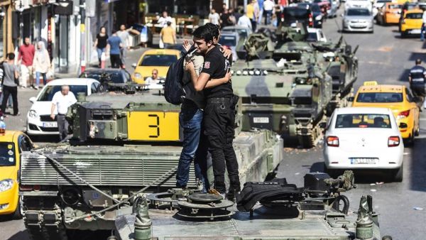 A police officer embraces a man on abandoned tank at Uskudar in Istanbul Saturday. (AFP/Bulent Kilic) 