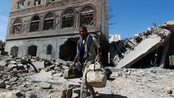A Yemeni man carries his bags through the ruins of buildings destroyed in an air strike by the Saudi-led coalition in the capital Sanaa on October 28, 2015. (AFP/Mohammed Huwais)