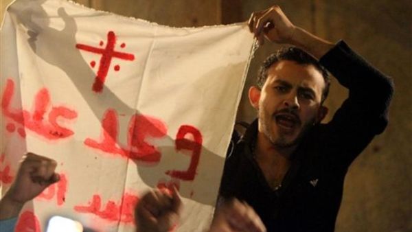 أحد الأقباط المصريين يرفع لافتة رسم عليها الصليب.