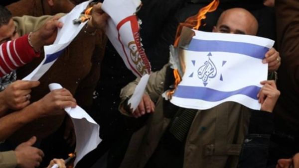 مناصرون للرئيس الفلسطيني عباس يحرقون علما يظهر نجمة شعار قناة الجزيرة مرسوما وسط نجمة داود في العلم الإسرائيلي!!