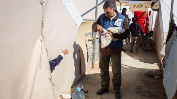 A volunteer from a Lebanese NGO distributes bread to Syrian refugees (AFP/File Photo)	