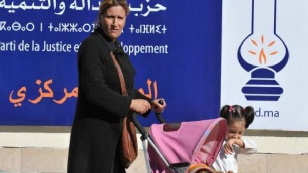 امراة تعبر مع اطفالها من امام لافتة انتخابية في الرباط
