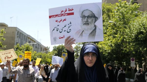 An Iranian protestor holds a banner bearing a portrait of top Bahraini Shiite cleric Isa Qassim, who was sentenced on May 21 to a suspended one-year jail term, during a demonstration in the capital Tehran on May 26, 2017 (STR/AFP)