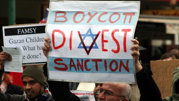 Protesters hold placards in support of the Boycott, Divestment, and Sanctions (BDS) movement. (Wikimedia)