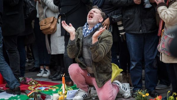 A man reacts as people gather to observe a minute of silence in memory of the victims of the Brussels airport and metro bombings, on the Place de la Bourse in central Brussels, on March 23, 2016, a day after the triple blasts killed some 30 people and left around 250 injured. (AFP/Aurore Belot)