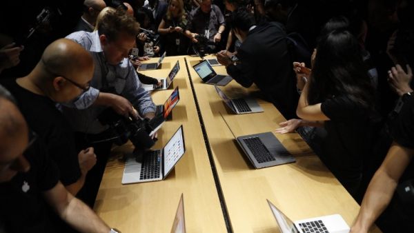 Members of the media gather around a table displaying the new Apple MacBook Pro laptop after the product launch event on October 27, 2016 in Cupertino, California. (AFP/Stephen Lam)