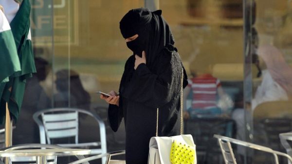 A Saudi woman looks at her mobile as she walks through a coffee shop. (AFP/File)