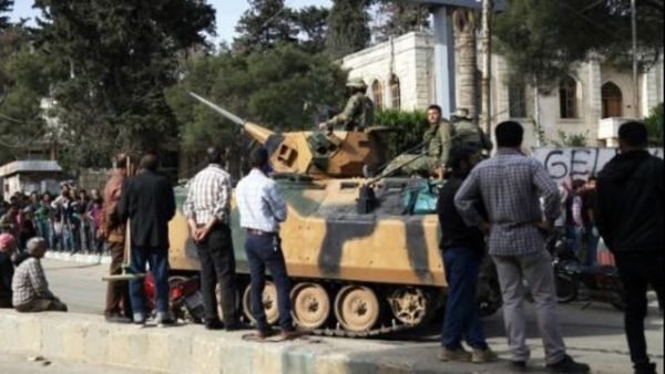 سوريون ينظرون الى دبابة تركية اثناء انتظارهم للحصول على مساعدات غذائية في عفرين 
