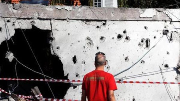 رجل ينظر إلى جدار تحطم جراء سقوط الصواريخ عليه من قطاع غزة في مدينة عسقلان بجنوب إسرائيل
