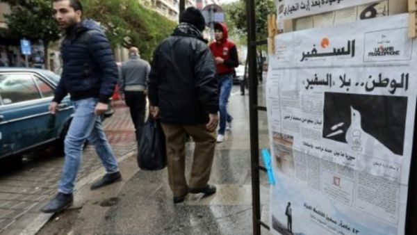مارة بجانب نسخة من العدد الاخير من صحيفة "السفير" في منطقة الحمرا في بيروت

