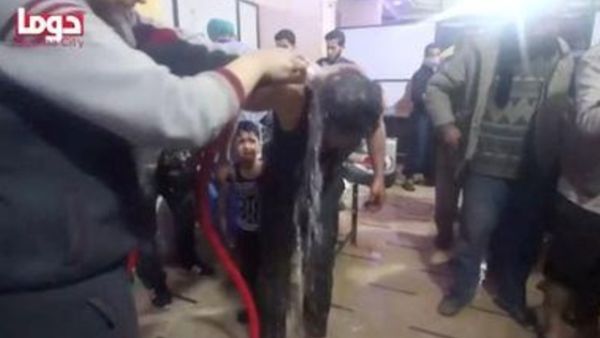 رجل يتم غسله بالماء بعد هجوم يشتبه أنه كيماوي في ما يعتقد أنها دوما في الغوطة الشرقية بسوريا 
