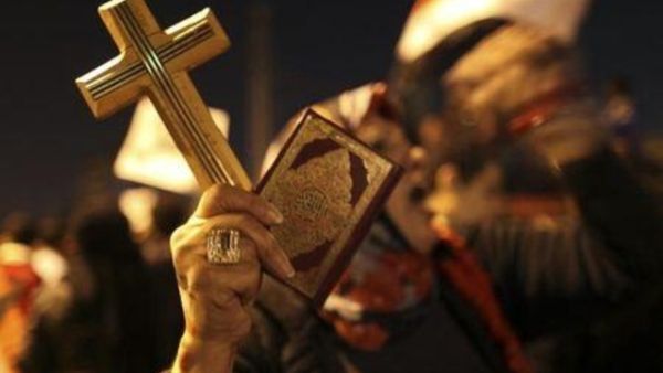 امرأة تحمل مصحفا وصليبا خلال مظاهرة في القاهرة
