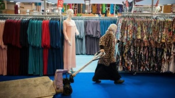 امرأة محجبة تمر من أمام ملابس للبيع خلال الاجتماع السنوي لمسلمي فرنسا شمال باريس 
