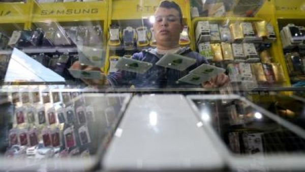 فلسطيني يعرض شرائح للهاتف المحمول تابعة لشركة جوال الفلسطينية في متجر بمدينة غزة
