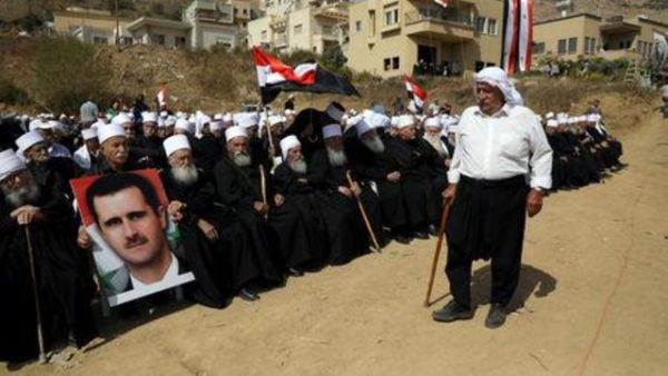 أشخاص من الدروز العرب ينظمون مسيرة ويرفعون صورة للرئيس السوري بشار الأسد قرب خط وقف إطلاق النار بين إسرائيل وسوريا في هضبة الجولان
