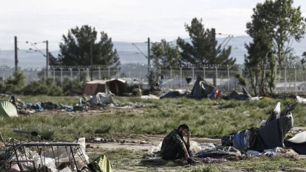 A refugee sits on the ground near destroyed tents during a police operation to clear a makeshift camp for refugees and migrants at the border between Greece and Macedonia near the village of Idomeni, northern Greece on May 25, 2016. (AFP/Yannis Kolesidis)