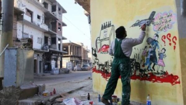 فنان سوري يرسم جدارية تمثل الحرب في بلاده، في احد شوارع بنش قرب ادلب
