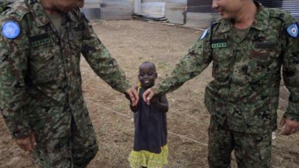 مهندسان من قوة الدفاع الذاتي اليابانية التابعة لقوات الامم المتحدة لحفظ السلام يداعبان طفلة في مركز للأطفال في جوبا بجنوب السودان
