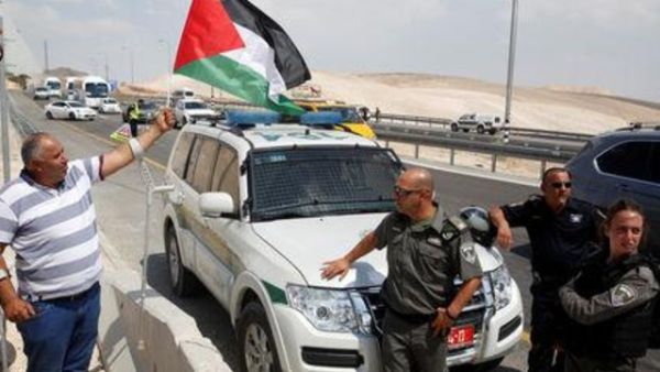 متظاهر يرفع العلم الفلسطيني في وجه جنود إسرائيليين أثناء احتجاج على خطط لهدم قرية الخان الأحمر بالضفة الغربية

