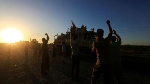 أشخاص يتجمعون على الطريق يرحبون بقوات الأمن العراقية الذين يواصلون التقدم على متن حافلات عسكرية في كركوك
