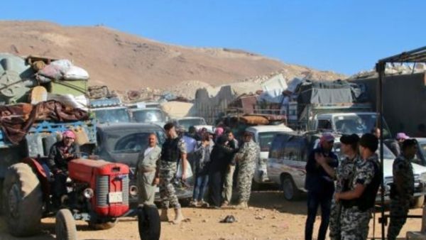 عناصر من الأمن اللبناني بالقرب من سيارات تقل لاجئين سوريين يستعدون لمغادرة لبنان
