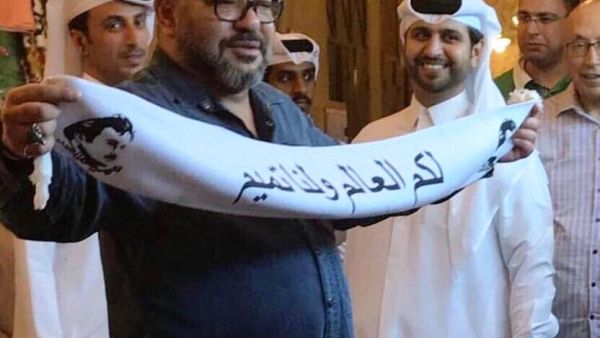 ملك المغرب يرفع وشاحا كتب عليه شعار "لكم العالم ولنا تميم"


