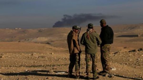 دخان متصاعد وراء أفراد من قوات التدخل السريع العراقية جراء معارك مع تنظيم الدولة الإسلامية إلى الجنوب من الموصل يوم الاثنين
