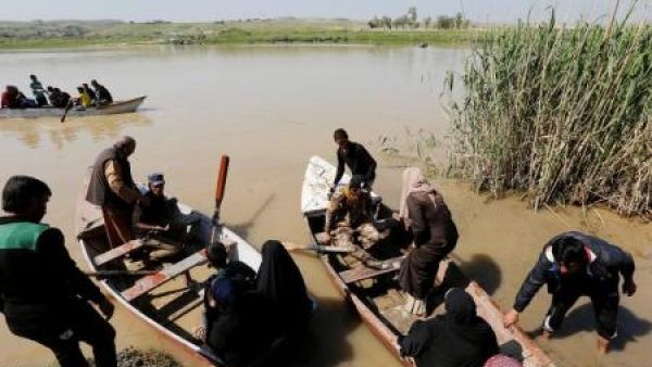 نازحون عراقيون يعبرون نهر دجلة باستخدام قارب بعد أن أغلقت فيضانات جسور الموصل
