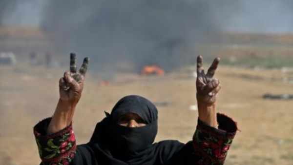 امرأة فلسطينية ترفع شارة النصر خلال احتجاجات على حدود قطاع غزة مع اسرائيل
