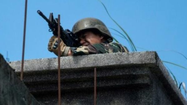 جندي فيلبيني يصوب سلاحه نحو مواقع المسلحين الإسلاميين من فوق سطح بناية في مدينة ملاوي

