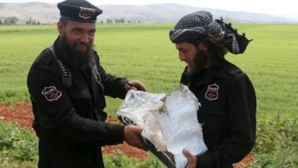 شرطيان من جبهة النصرة يعملان ضمن جماعة تسمى جيش الفتح. بحملان بقايا عبوة ناسفة عثر عليها على أطراف طريق يربط إدلب بمنطقة أرمناز في سوريا

