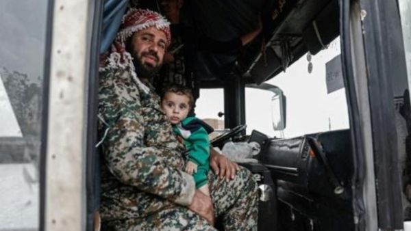 مقاتل سوري معارض يحمل طفله عند اجلائه من مدينة الضمير شرق دمشق عند وصوله على متن حافلة الى حلب بشمال البلاد

