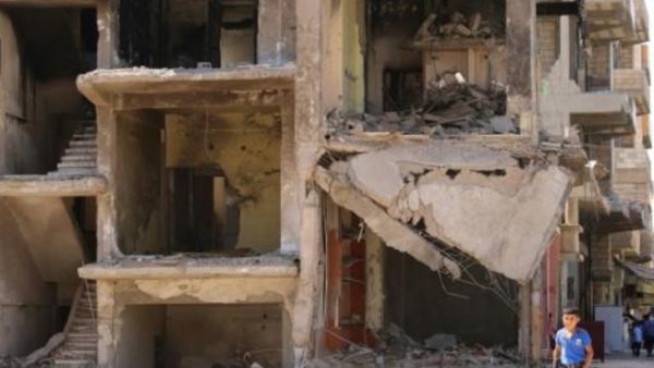 ارشيف/ طفل يمر امام مبنى مدمر في القامشلي