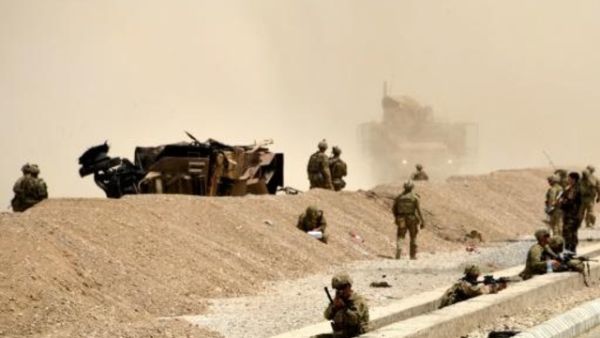 جنود اميركيون يراقبون على مقربة من آليتهم التي دمرت في هجوم انتحاري لطالبان في قندهار
