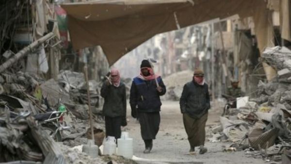 سوريون يسيرون وسط الدمار في مدينة الرقة
