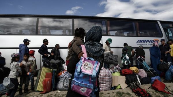 Refugees stand near a bus as they wait to be transferred to a hospitality center during a police operation at a refugee camp at the border between Greece and Macedonia, near the village of Idomeni on May 25, 2016. (AFP/Yannis Kolesidis)